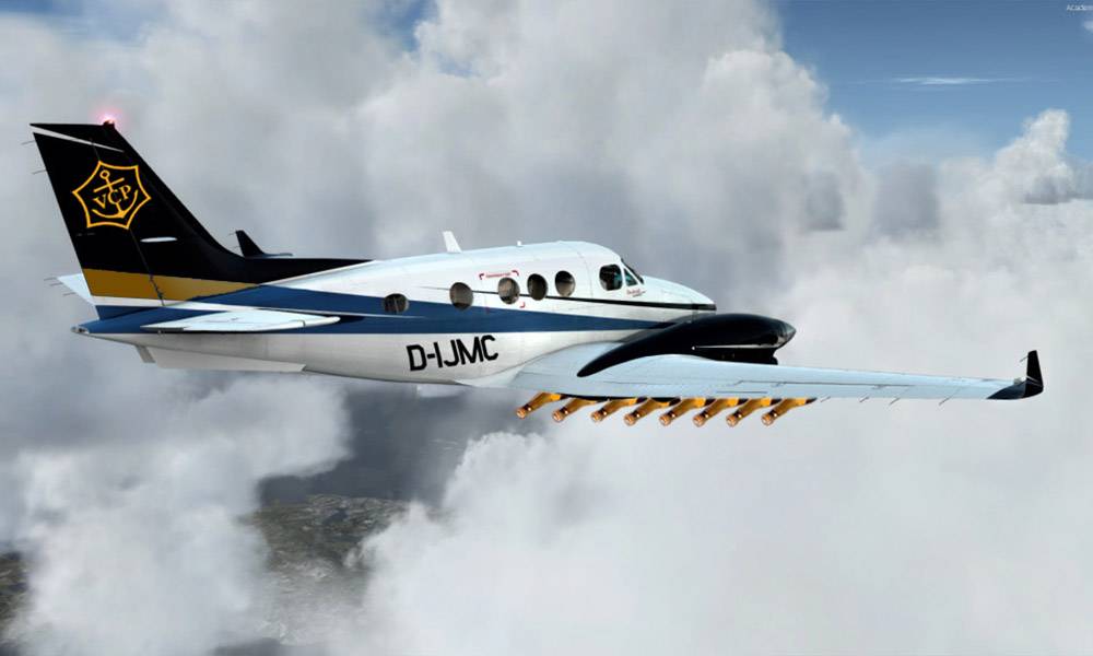 A small private plane with customized tail art flying above clouds, dispensing material from its wings.