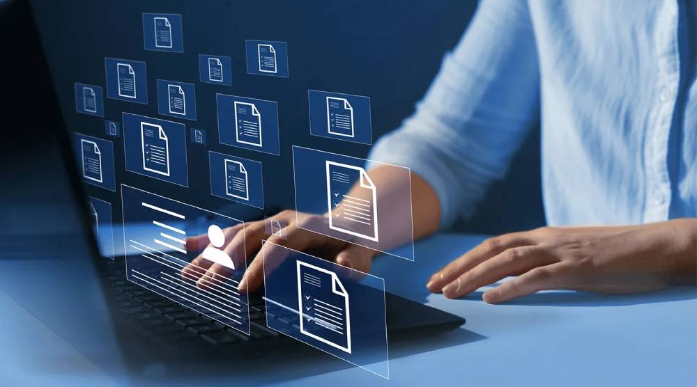 Person using a laptop with floating digital icons of documents around them, symbolising file management or data organisation.