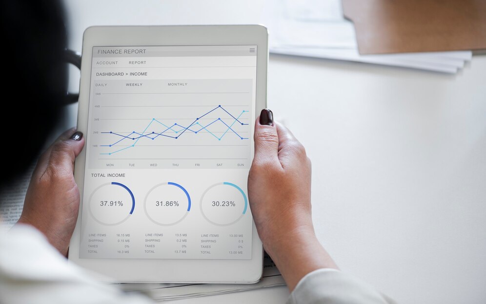 Person holding a tablet displaying finance reports with charts and graphs.
