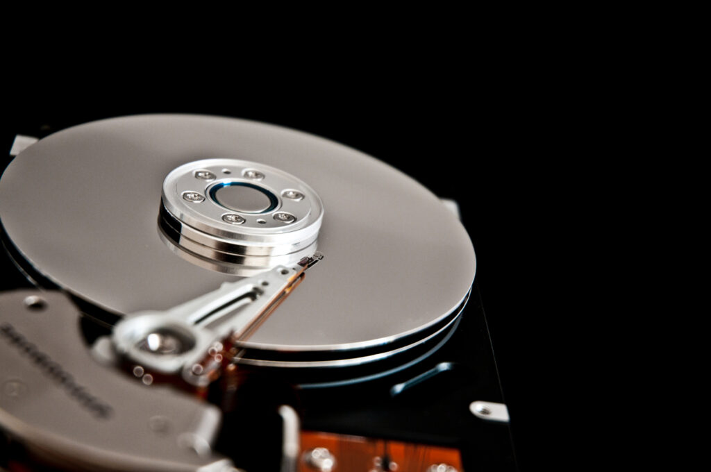 Close-up view of a hard drive with a shiny platter and read/write arm, set against a black background.