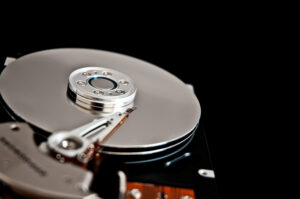 Close-up view of a hard drive with a shiny platter and read/write arm, set against a black background.