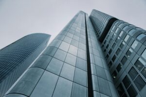 Low-angle view of towering modern skyscrapers with reflective glass facades against a grey sky.