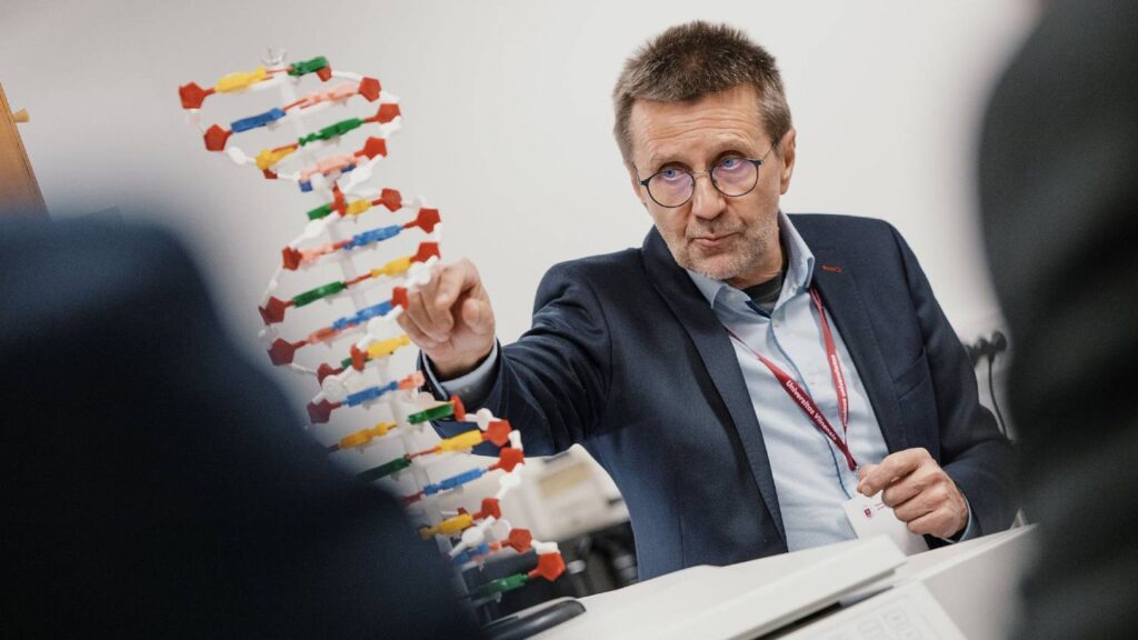 A professor explaining a DNA model during a lecture.