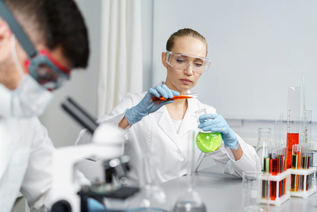 Female scientist conducting an experiment with colorful chemical solutions in a laboratory setting.