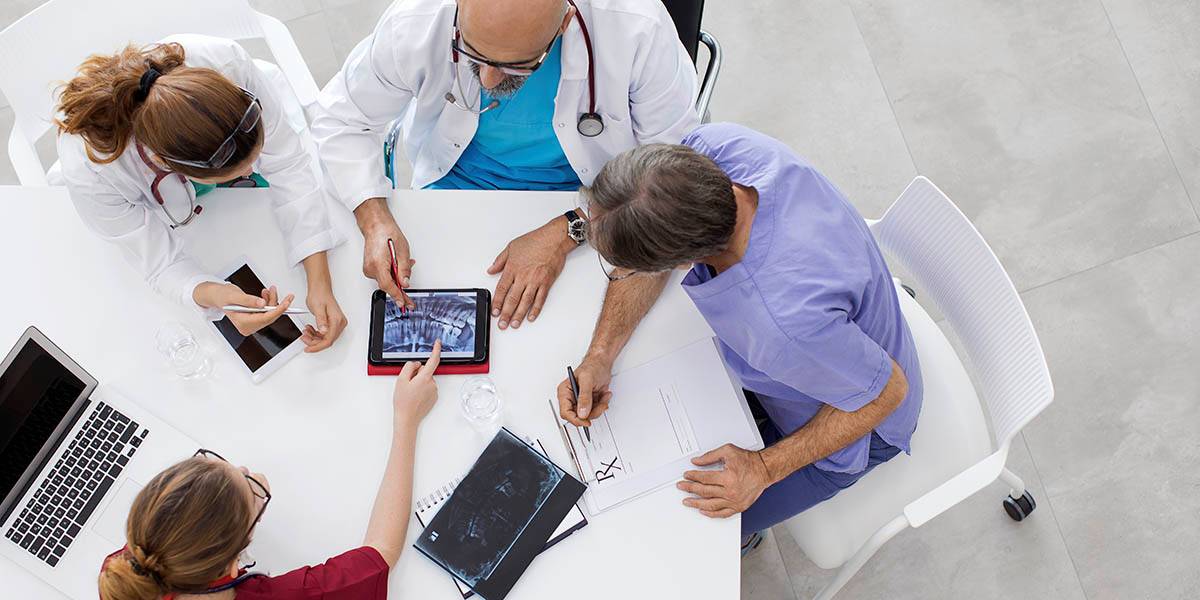 Medical team discussing over digital tablets and X-ray images in a modern clinic.