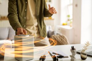 Person interacting with a smart speaker on a desk, surrounded by swirling orange light effects.